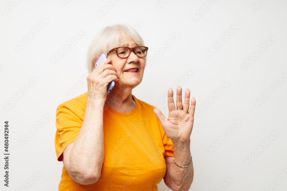 Portrait of an old friendly woman happy lifestyle in yellow t-shirts isolated background Portrait of an old friendly woman happy lifestyle in yellow t-shirts isolated background