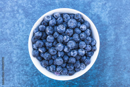 Bowl of fresh blueberries isolated on blue background.
