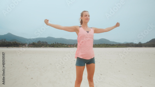 Fitness girl stretching body joints warm up on tropical beach