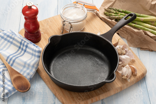Cast iron skillet on a wooden board with kitchen items. photo