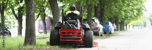 The lawn mower stands on sidewalk near the lawn photo