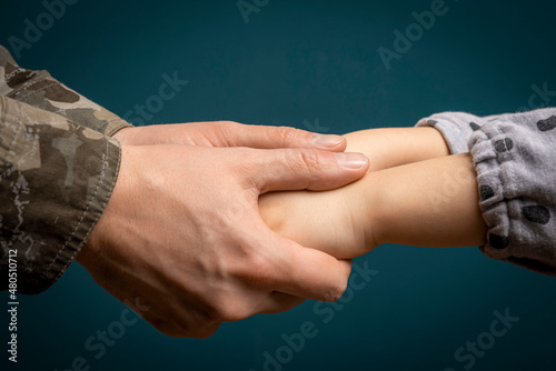 A soldier's hand holds a child's hand in close-up. My father is a military man. A soldier and a child. Father's love