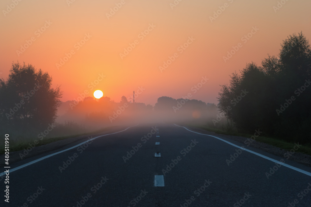 Empty Road Leading to Golden Sunrise on Foggy Morning
