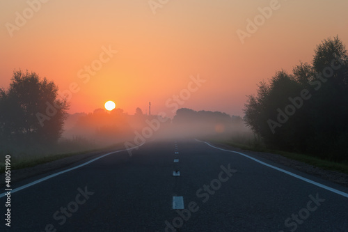 Empty Road Leading to Golden Sunrise on Foggy Morning