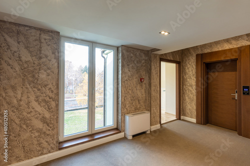 Interior of a carpeted hotel corridor doorway with brown wooden doors © rilueda