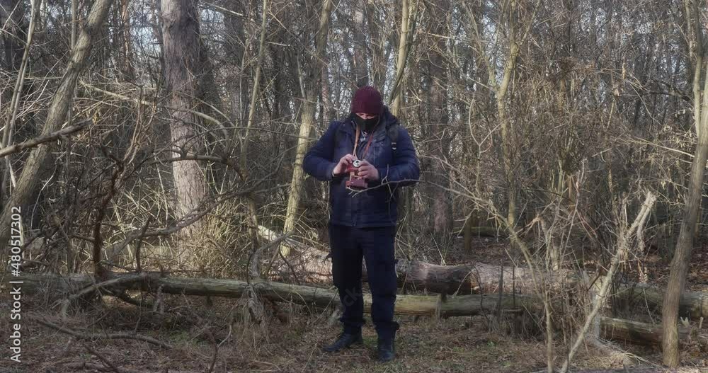 a traveler in a protective mask takes pictures in a pine forest on a retro camera a traveler in a protective mask takes pictures in a pine forest on a retro camera