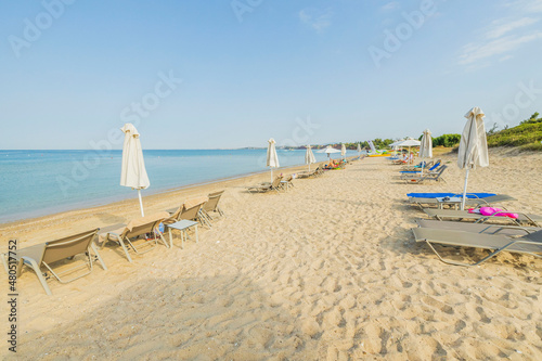 Beautiful view of white sandy beach of Greece with empty sunbeds and umbrellas. Greece. 