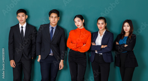 Portrait studio shot group of Asian professional male female teacher or college students in formal suit outfit standing crossed arms smiling look at camera on green chalkboard background in classroom