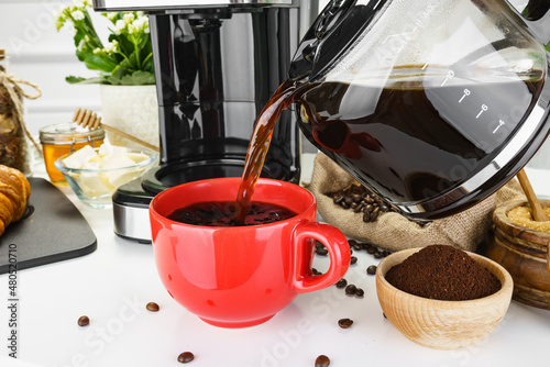 Nalewanie kawy do czerwonego kubka.