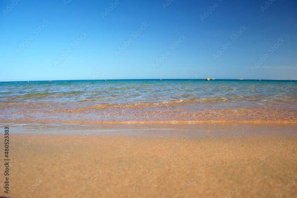 Seascape with surface of blue sea water with small ripple waves crashing on yellow sandy beach. Travel and vacations concept Seascape with surface of blue sea water with small ripple waves crashing on yellow sandy beach. Travel and vacations concept