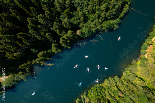 Aerial view with a group of tourists which are exploring by boat a beautiful lake in the heart of the forest.