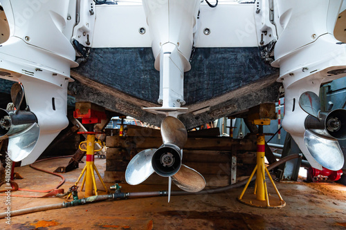 Three outboard motors mounted on a transom mount at the stern of the boat in dry dock. photo