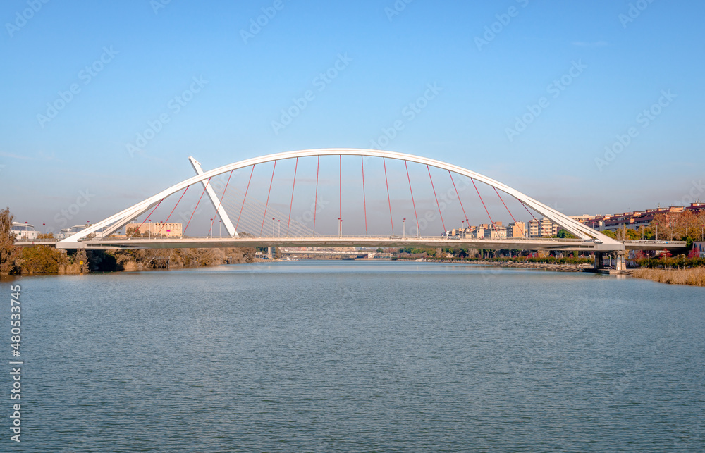 Panoramic view of Barqueta Bridge, a tied arch bridge which spans the Alfonso XIII channel of the Guadalquivir river in Seville, Andalusia, Spain. Panoramic view of Barqueta Bridge, a tied arch bridge which spans the Alfonso XIII channel of the Guadalquivir river in Seville, Andalusia, Spain.