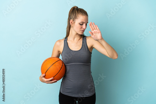 Young woman playing basketball isolated on blue background making stop gesture and disappointed