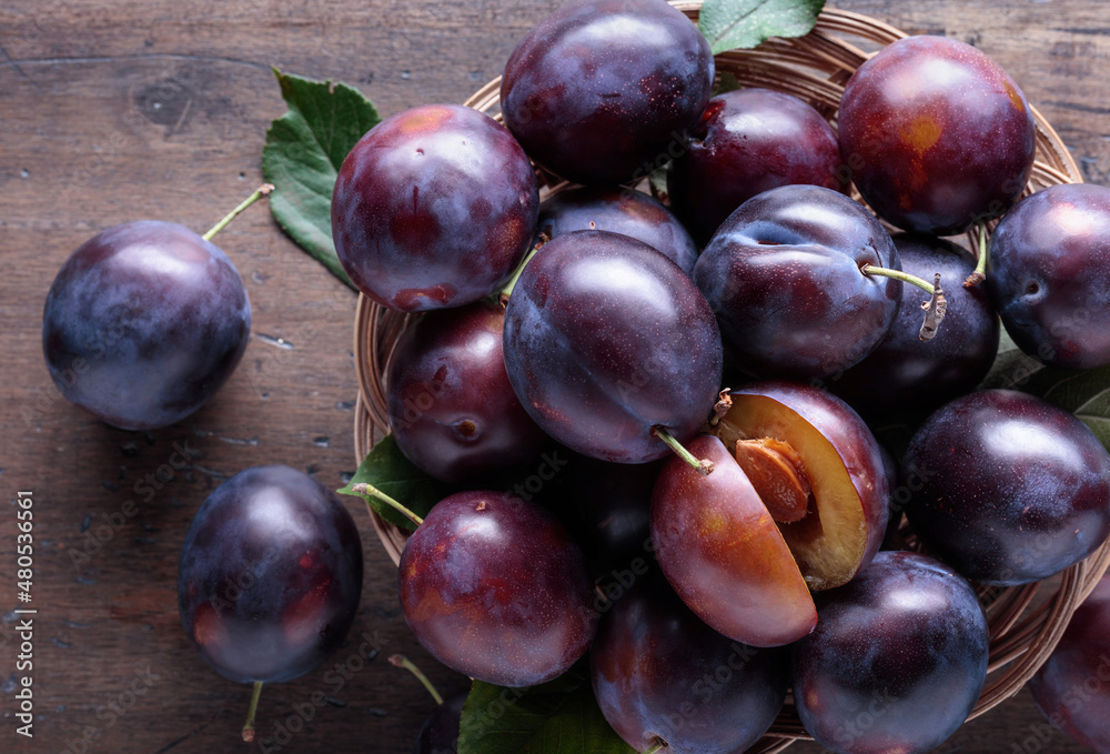 Fototapeta premium Ripe juicy plums on a wooden background.
