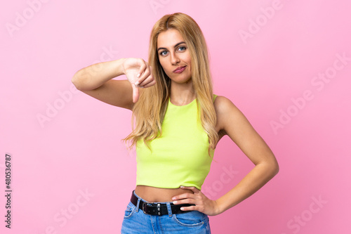 Young Uruguayan blonde woman over isolated pink background showing thumb down with negative expression