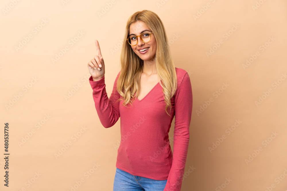 Young Uruguayan blonde woman over isolated background showing and lifting a finger in sign of the best Young Uruguayan blonde woman over isolated background showing and lifting a finger in sign of the best