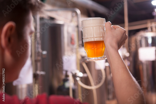 Foto Cropped close up of a brewer examining quality of freshly brewed beer in a mug