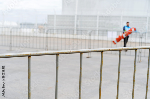 A fragment of a metal fence on a sports ground during the installation of mobile structures. Preparation for street competitions in various sports disciplines. Foreground