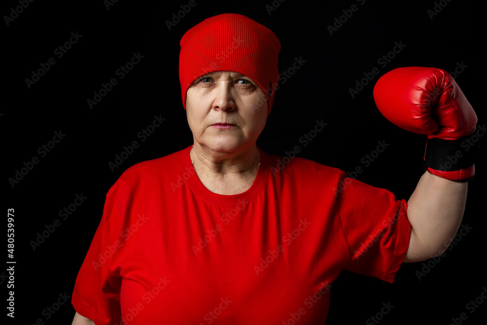 Elderly woman boxer in red on a black background.