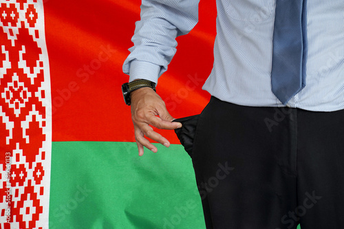 Man turns up his trouser pocket on the background of the Belarus flag