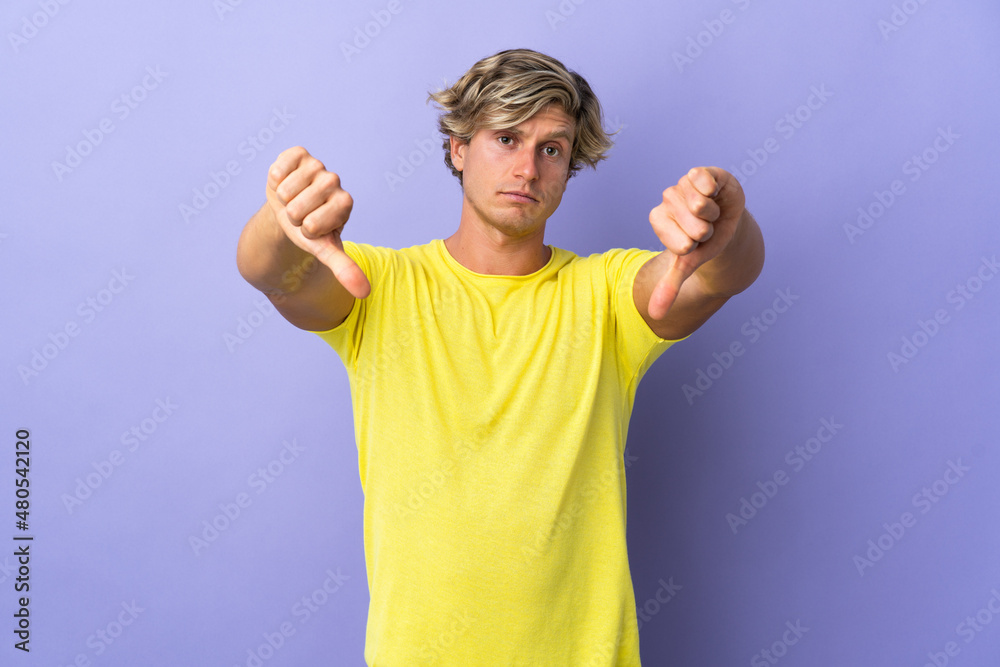 English man over isolated purple background showing thumb down with two hands English man over isolated purple background showing thumb down with two hands