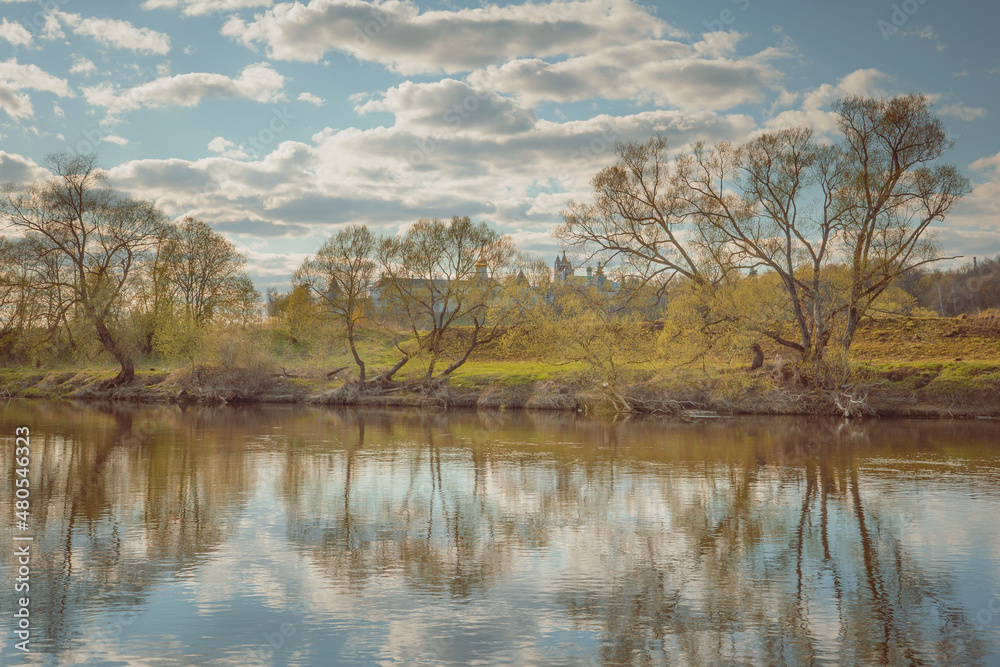 Spring landscape with river, old monastery, trees and clouds