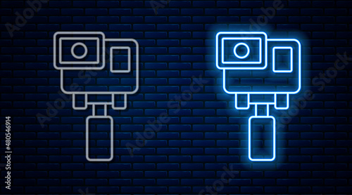 Glowing neon line Action extreme camera icon isolated on brick wall background. Video camera equipment for filming extreme sports. Vector