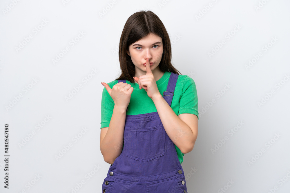 Young Russian woman isolated on blue background pointing to the side and doing silence gesture Young Russian woman isolated on blue background pointing to the side and doing silence gesture
