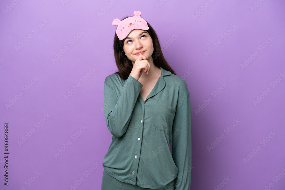 Young Russian woman in pajamas isolated on purple background and looking up Young Russian woman in pajamas isolated on purple background and looking up