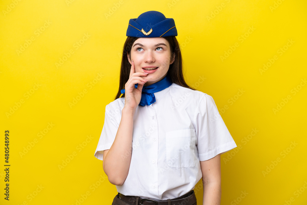Airplane stewardess Russian woman isolated on yellow background thinking an idea while looking up Airplane stewardess Russian woman isolated on yellow background thinking an idea while looking up