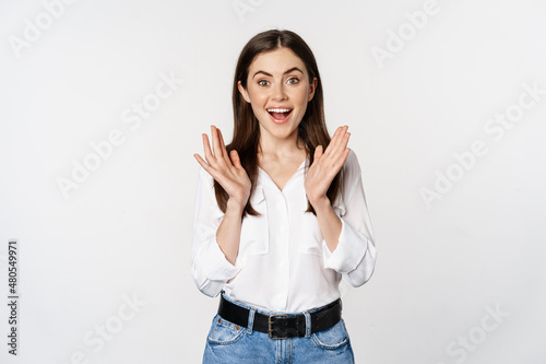 Enthusiastic laughing woman, smiling amused, clapping hands, applausing, standing in formal outfit over white background photo