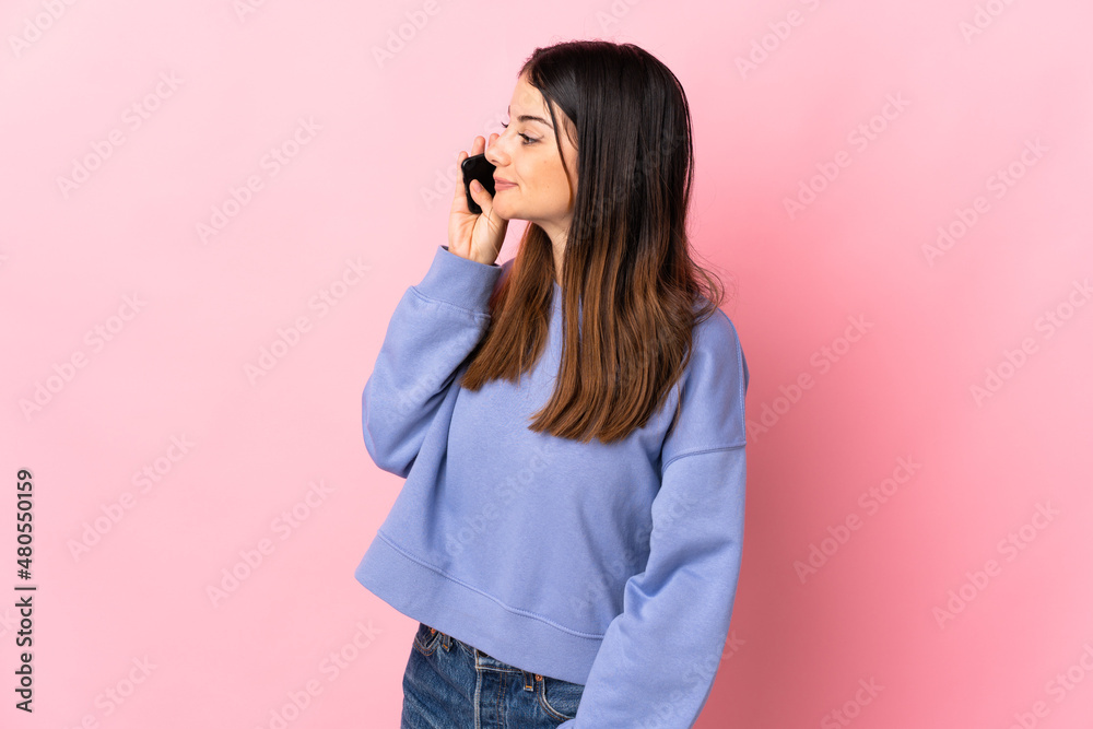 Young caucasian woman isolated on pink background keeping a conversation with the mobile phone with someone Young caucasian woman isolated on pink background keeping a conversation with the mobile phone with someone