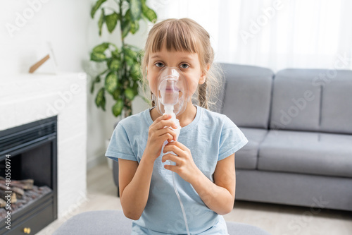 Slika na platnu Nine years old kid with allergic asthma, inhaling her medication through spacer