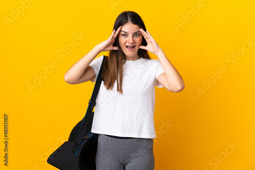 Young sport woman with sport bag isolated on yellow background with surprise expression