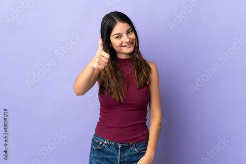 Young caucasian woman isolated on purple background with thumbs up because something good has happened