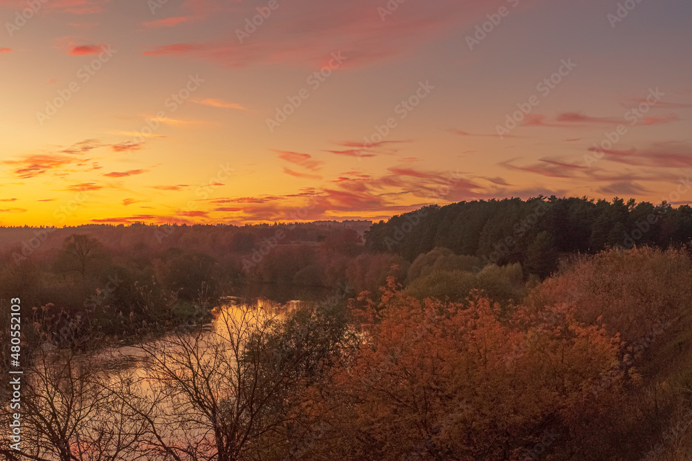 Beautiful autumn after sunset scene over the river with gradient orange to pink blue sky