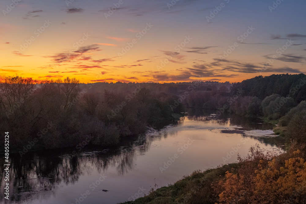 Beautiful autumn after sunset scene over the river with gradient orange to blue sky