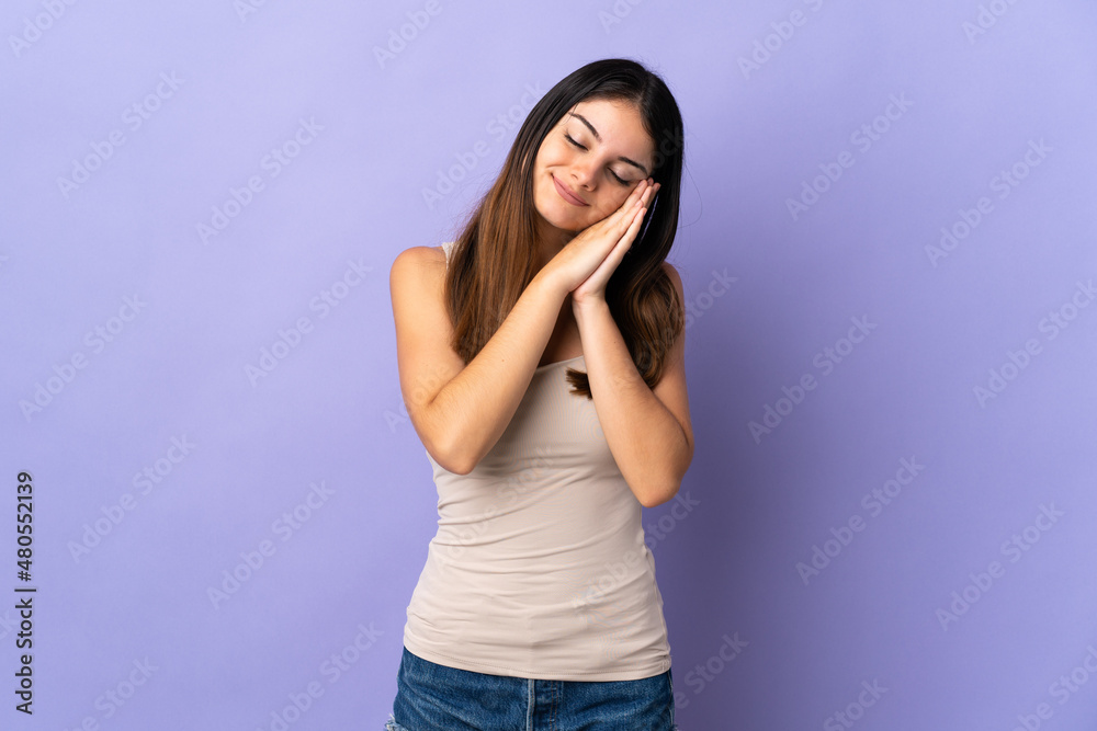 Young caucasian woman isolated on purple background making sleep gesture in dorable expression Young caucasian woman isolated on purple background making sleep gesture in dorable expression