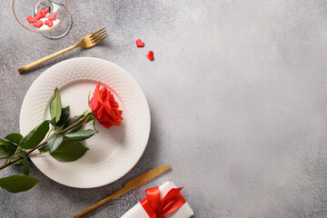 Valentine's day romantic dinner with red roses, gift and red rose flower on gray background. Top view. Copy space.
