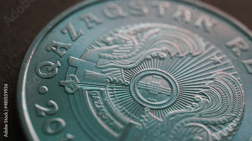 Translation  Kazakhstan. Kazakh 50 tenge coin with the country emblem and focus on shanyrak. Close-up. Green tinted background or wallpaper for Kazakh economy or state. Macro