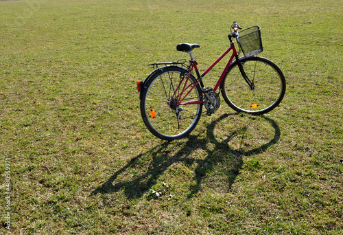 Red bike with basket on green grass