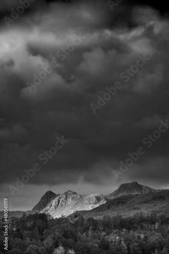 Black and white Majestic landscape image of stunning Autumn sunset light across Langdale Pikes looking from Holme Fell in Lake District