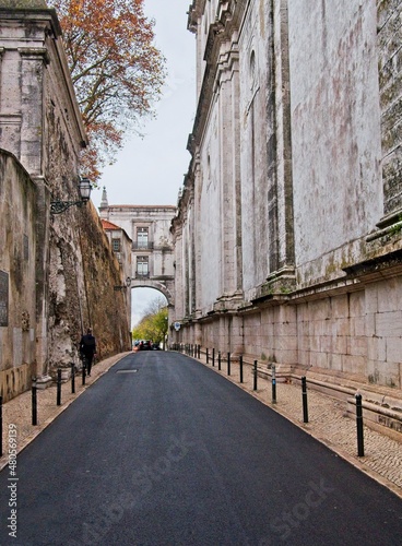 Vertical narrow road with pedestrian bridge connecting divided historical architectural buildings of St. Vincent Cathedral in the Graca neighbood of Lisbon, Portugal. photo
