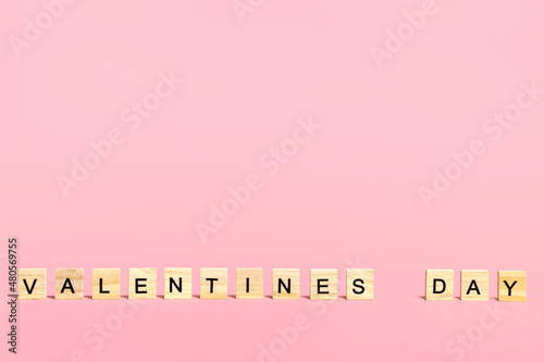 Inscription Valentine's Day in wooden letters on a pink background. 