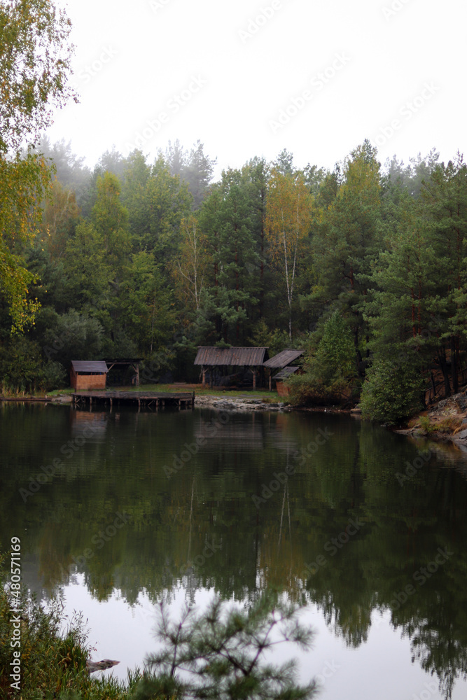 Wood house beside the lake in pine forest. Summer wooden lake house inside forest . Wood house beside the lake in pine forest. Summer wooden lake house inside forest .