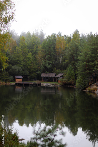 Wood house beside the lake in pine forest. Summer wooden lake house inside forest .