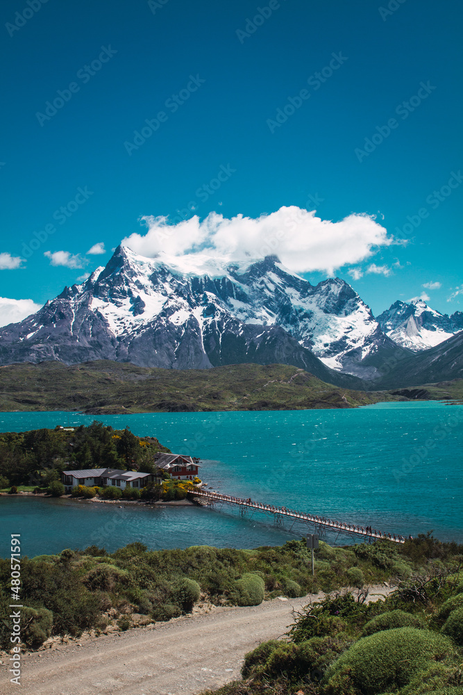Lake with a bridge to a house with snowy mountains in the background in the Torres del Paine area of ​​Chilean Patagonia