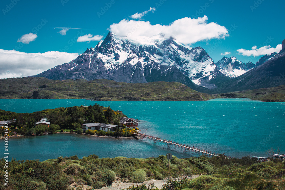 Lake with a bridge to a house with snowy mountains in the background in the Torres del Paine area of ​​Chilean Patagonia