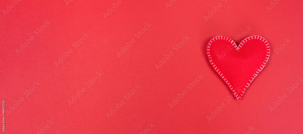 Heart on a red plain background. Valentine's day promotion long banner with copy space. Valentine's day concept background for postcard, sale banner, advertisement.